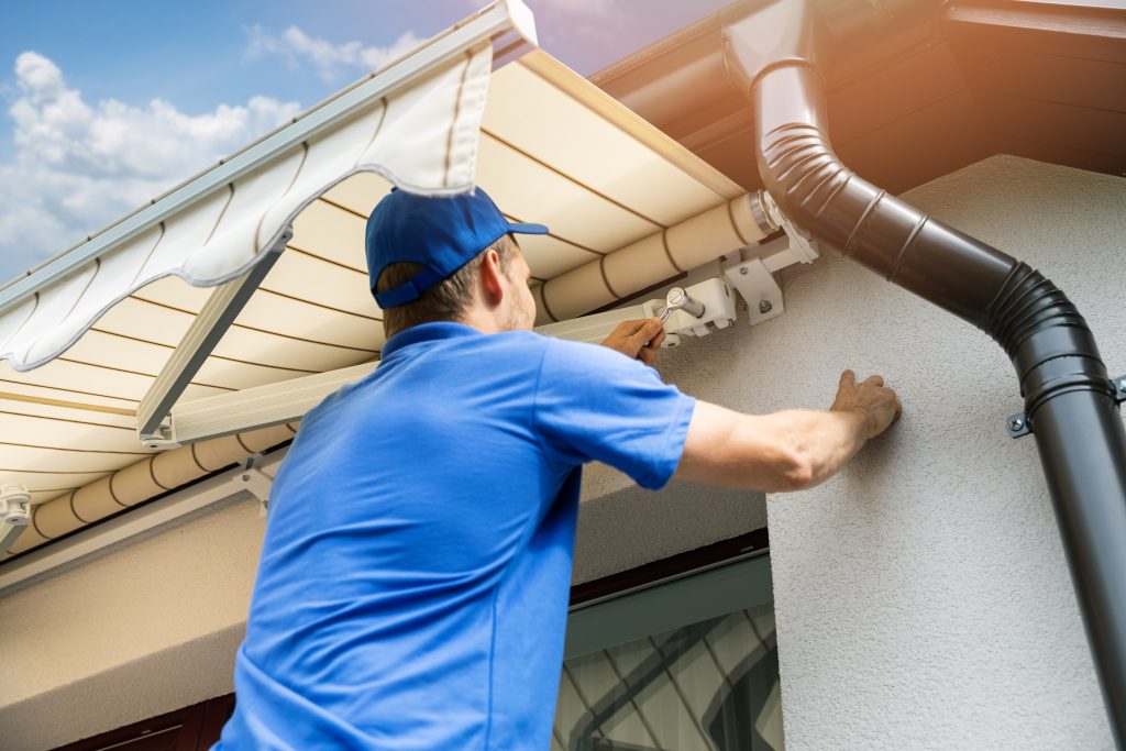 man putting up an awning outside